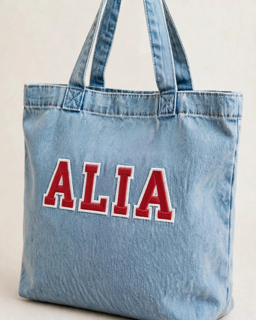 Light denim tote with small red patch letters – side angle view