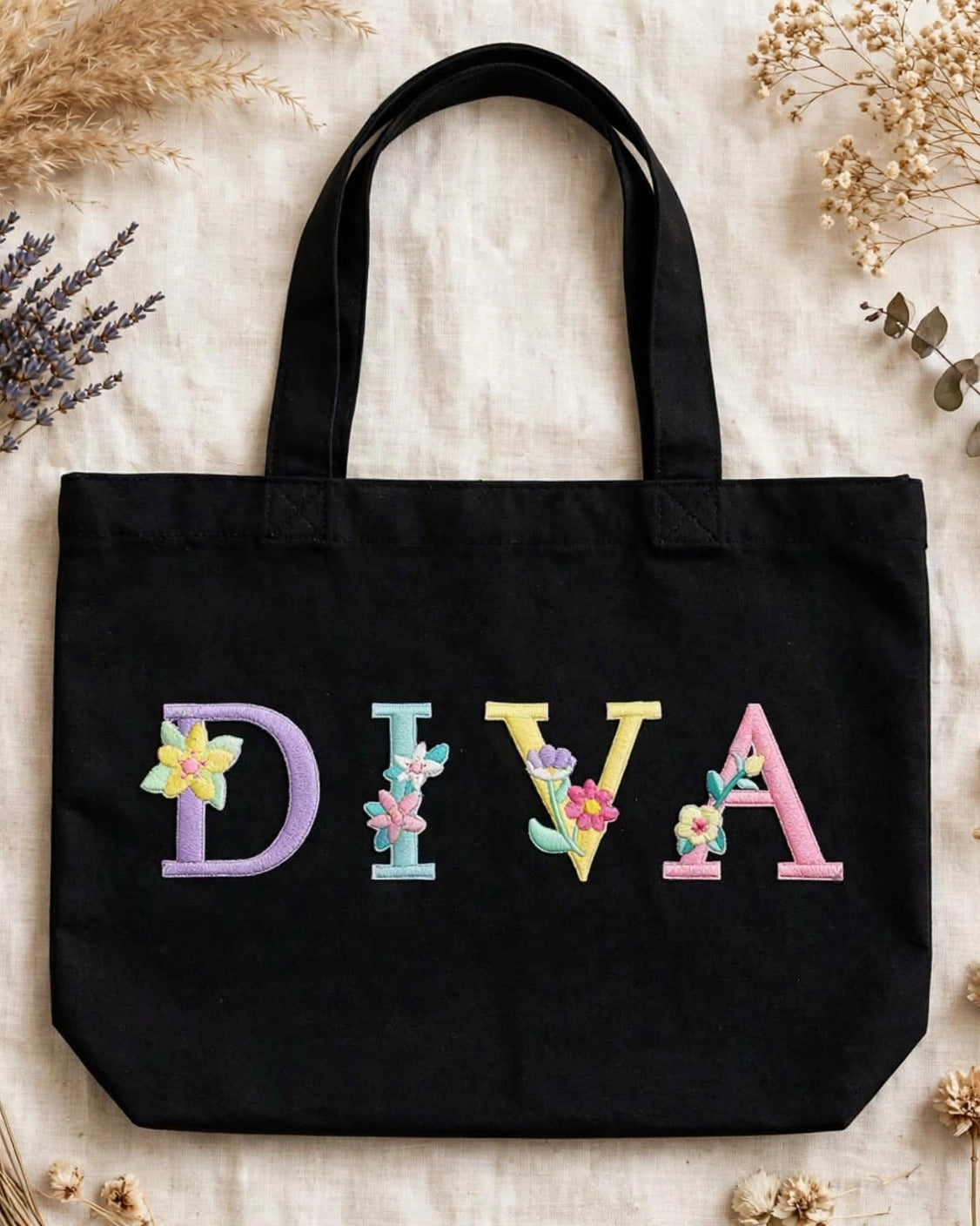 Black canvas tote with DIVA in pastel floral embroidered alphabet letters