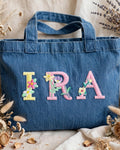 Denim blue canvas tote with IRA in pastel floral embroidered alphabet letters