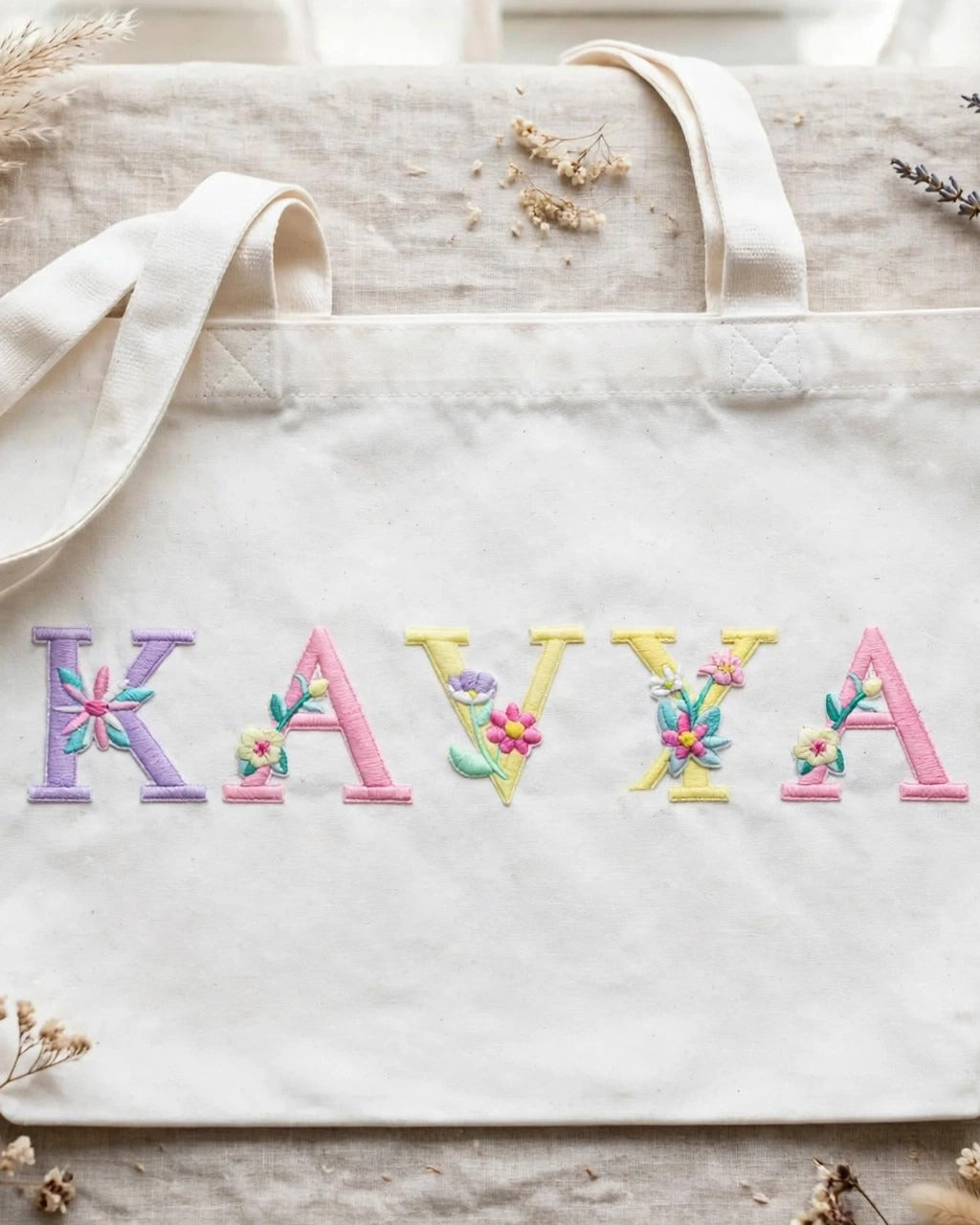 White canvas tote with KAVYA in pastel floral embroidered alphabet letters