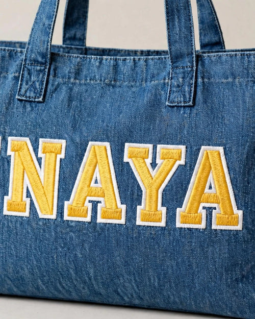 Medium denim tote with INAYA in yellow chunky patch letters - side view