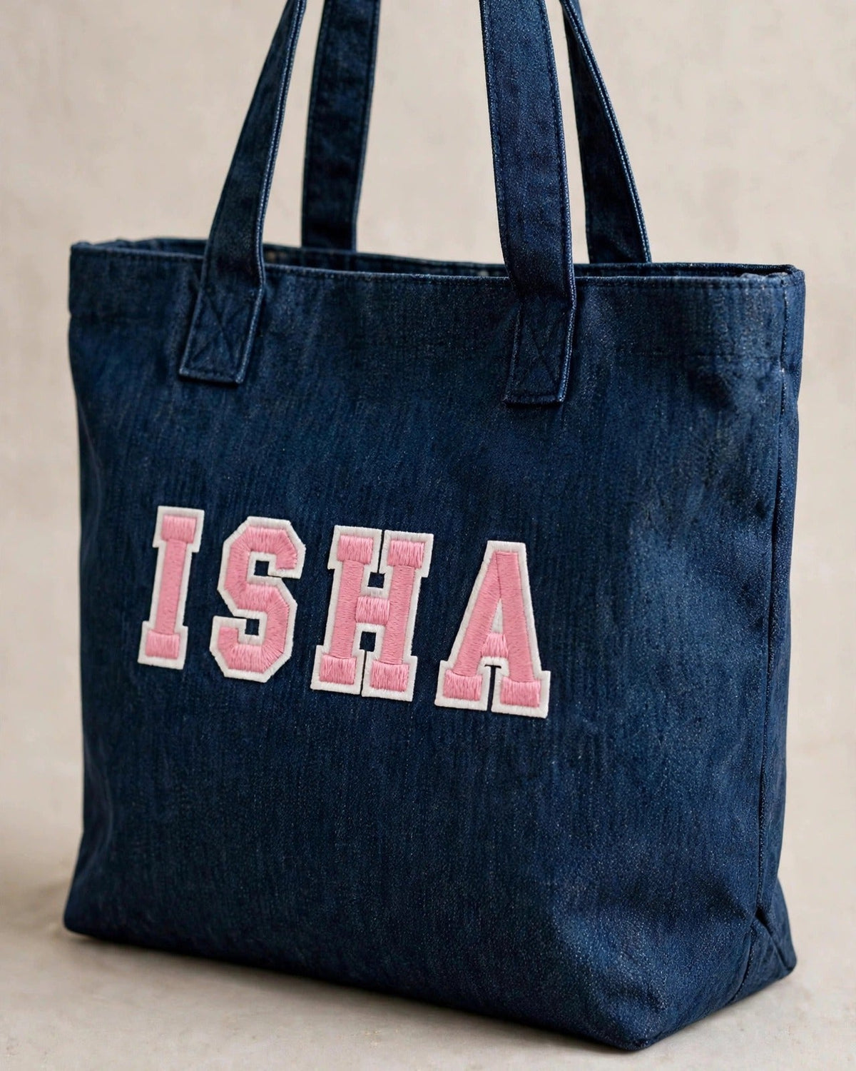Dark denim tote with small pink patch letters – side angle view