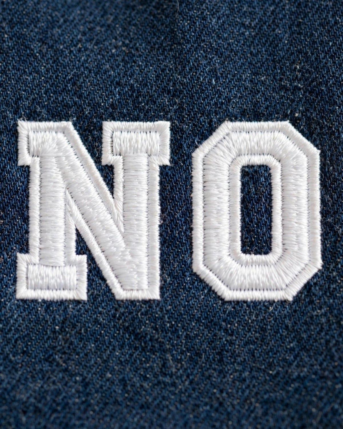 Dark denim tote with small white patch letters – embroidery close-up