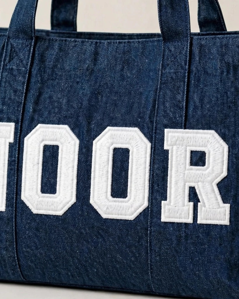 Dark denim tote with NOOR in white chunky patch letters - side view