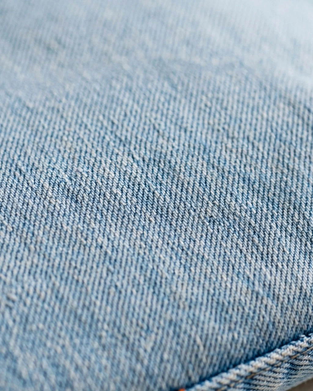 Light denim tote with small orange patch letters – fabric texture close-up