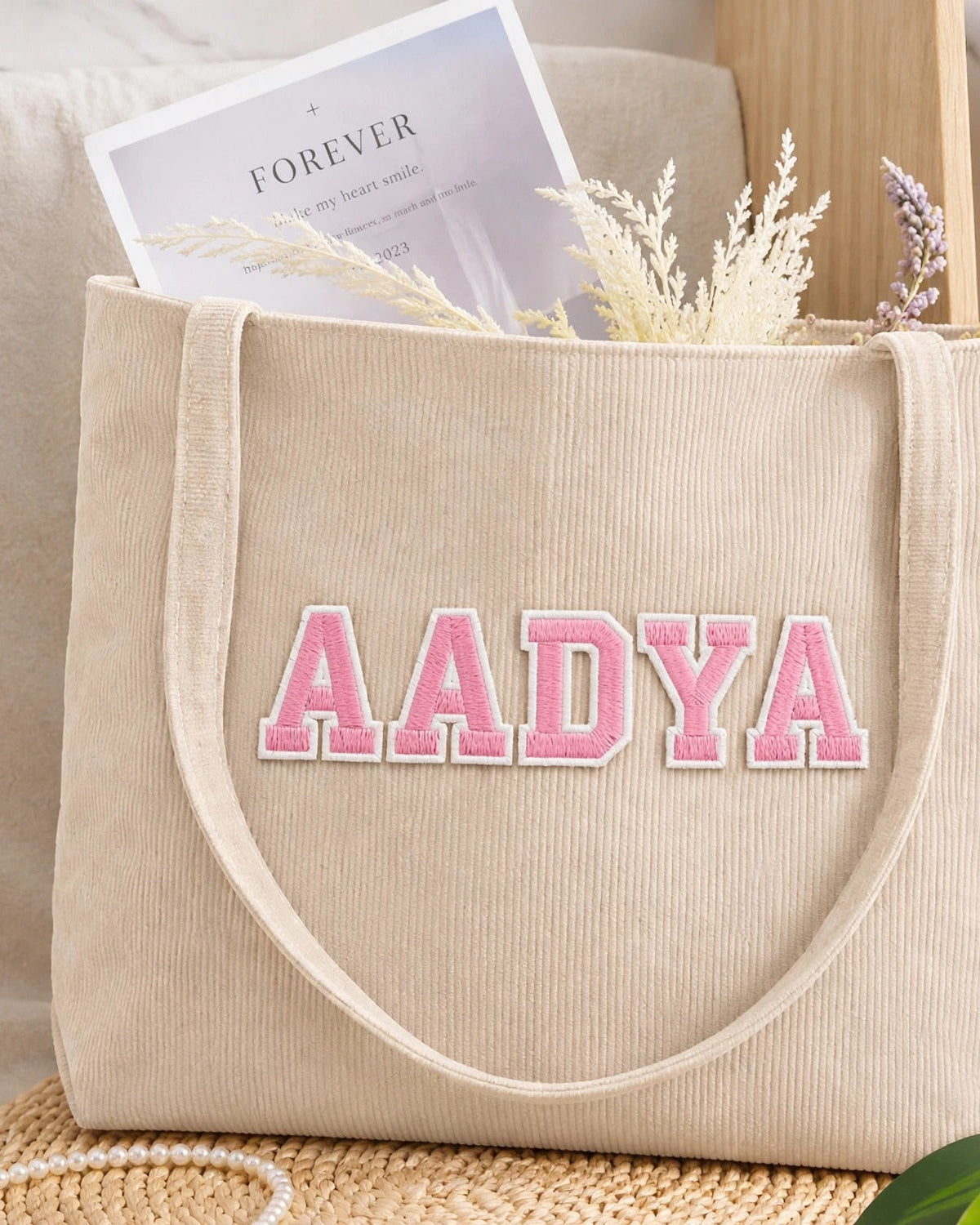 Beige corduroy tote with AADYA in pink embroidered varsity patch letters