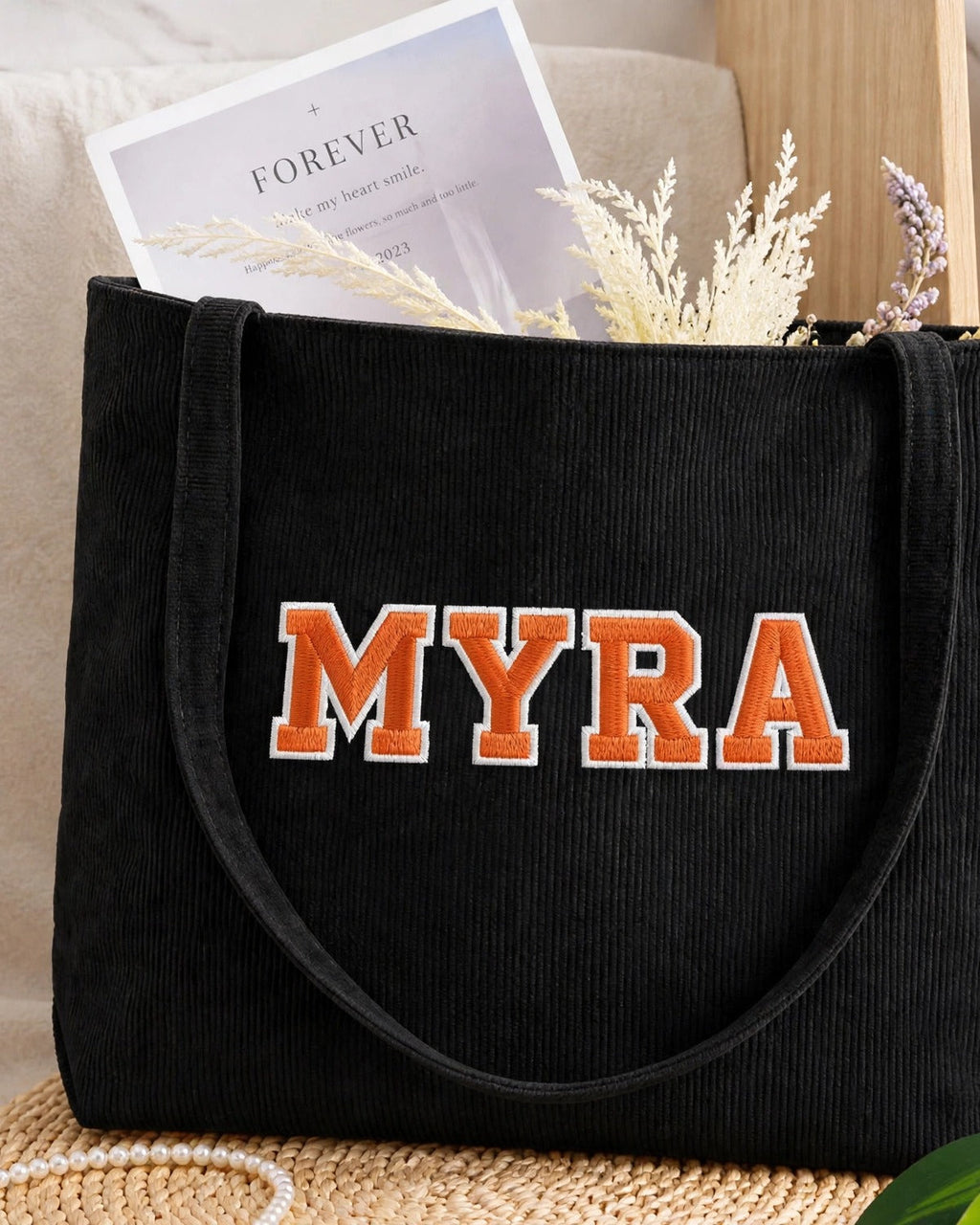 Black corduroy tote with MYRA in orange embroidered varsity patch letters