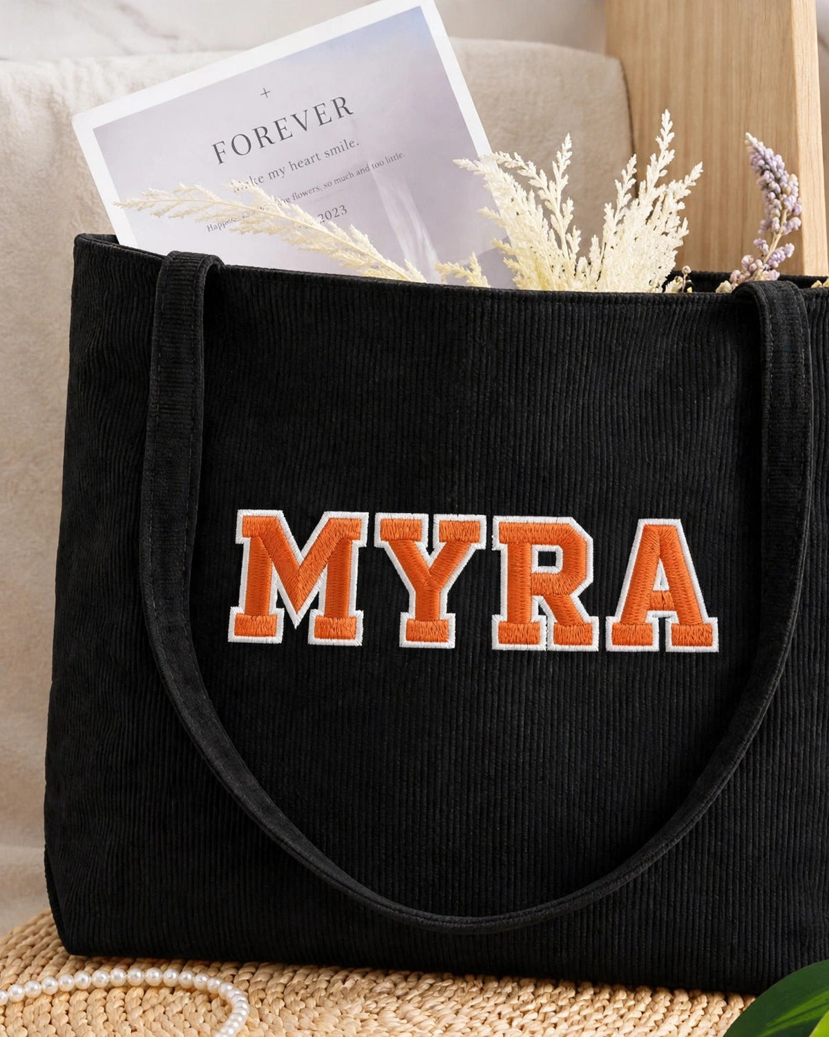 Black corduroy tote with MYRA in orange embroidered varsity patch letters