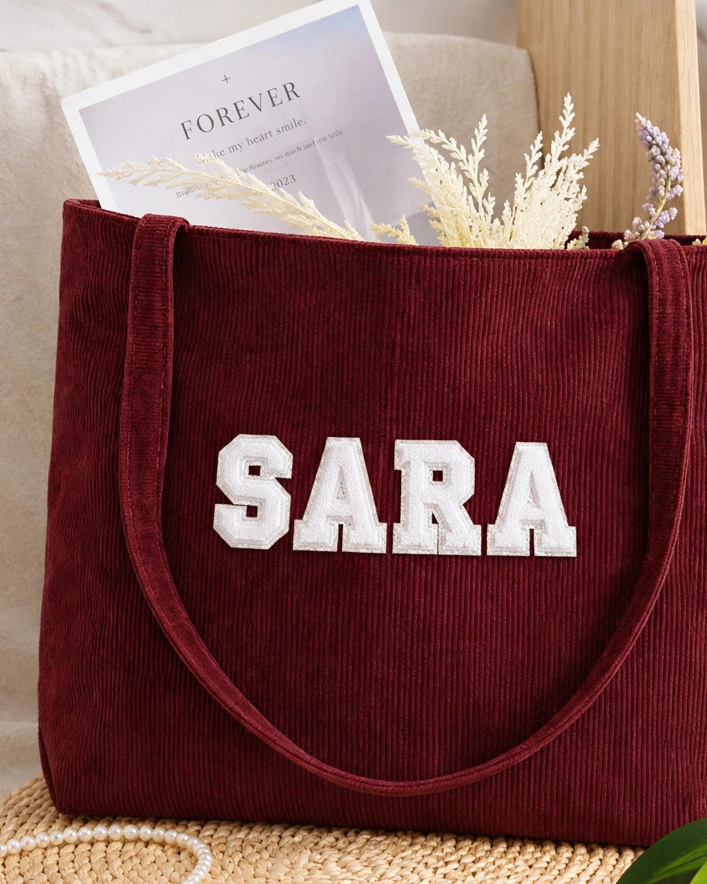 Maroon corduroy tote with SARA in white embroidered varsity patch letters