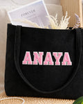 Black corduroy tote with ANAYA in light pink embroidered varsity patch letters