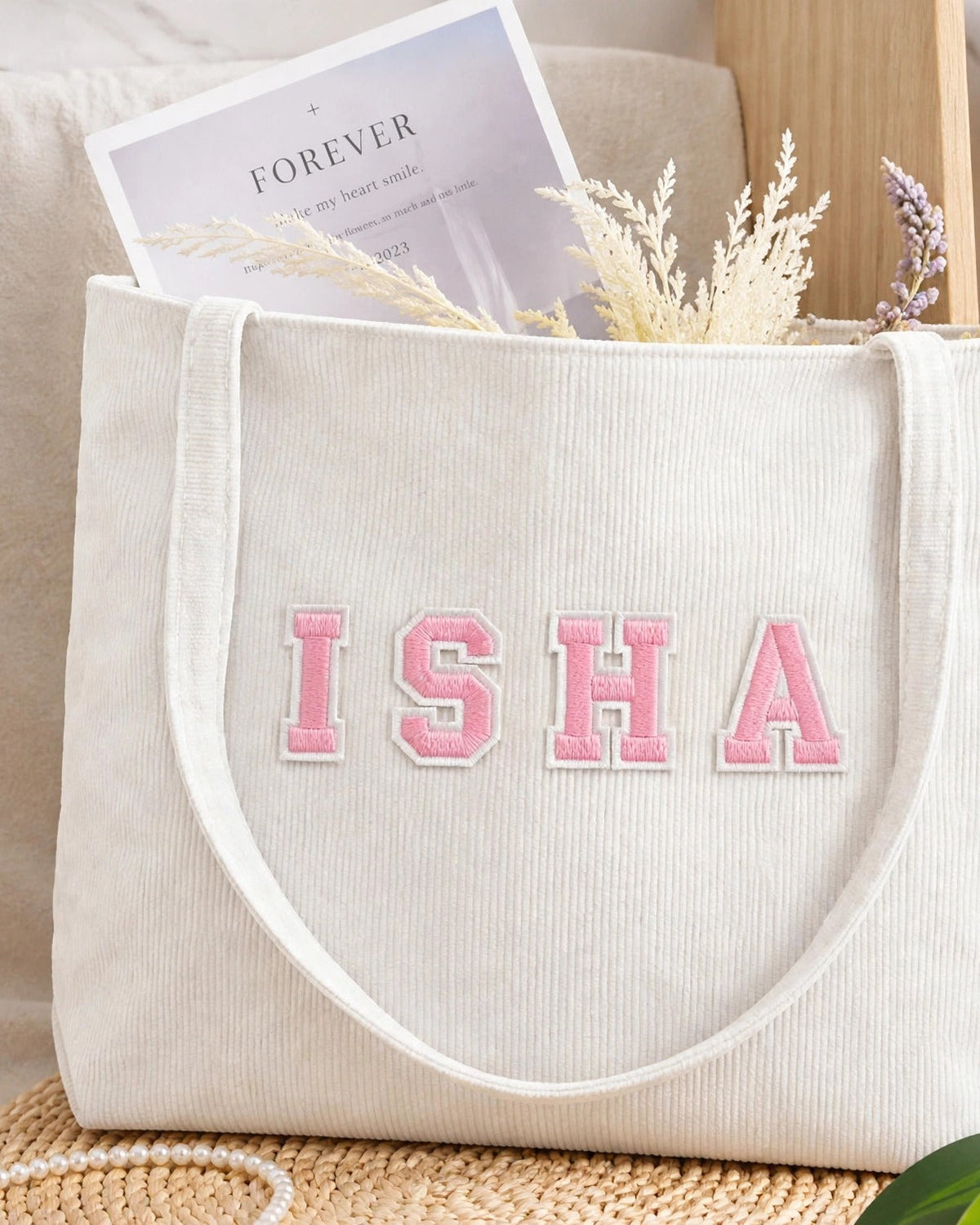 White corduroy tote with ISHA in light pink embroidered varsity patch letters